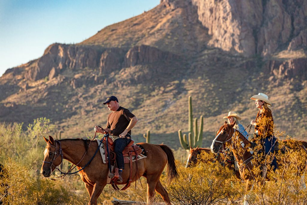 Mark Kelly and Gabby Giffords ride horses through a desert landscape.
