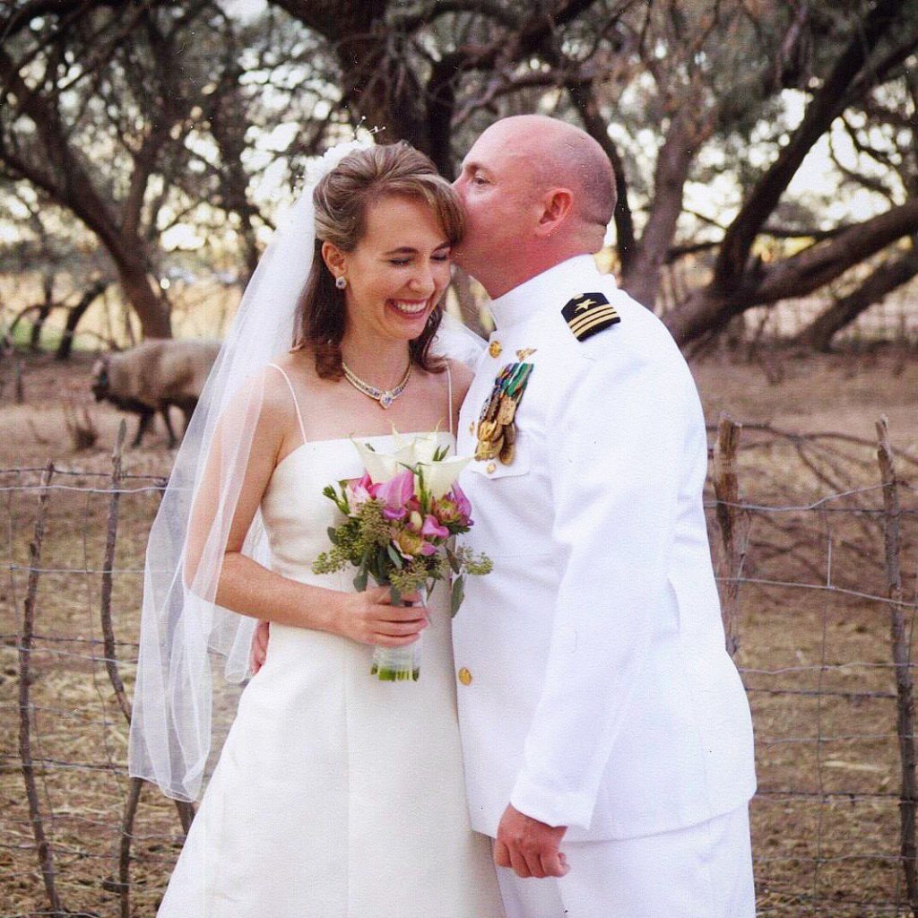 Mark Kelly and Gabby Giffords at their wedding in 2007. Gabby is smiling as Mark, wearing his Navy uniform, kisses her on the head.